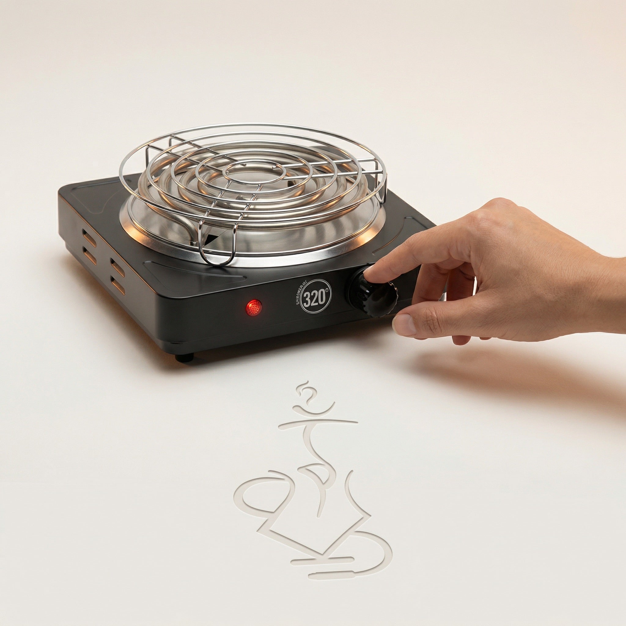 A hand resting on the 320 electric charcoal burner control knob in a warm white studio, showing the real-world size of the 1000W burner, brushed stainless coil and chrome safety grid available at The Premium Way.
