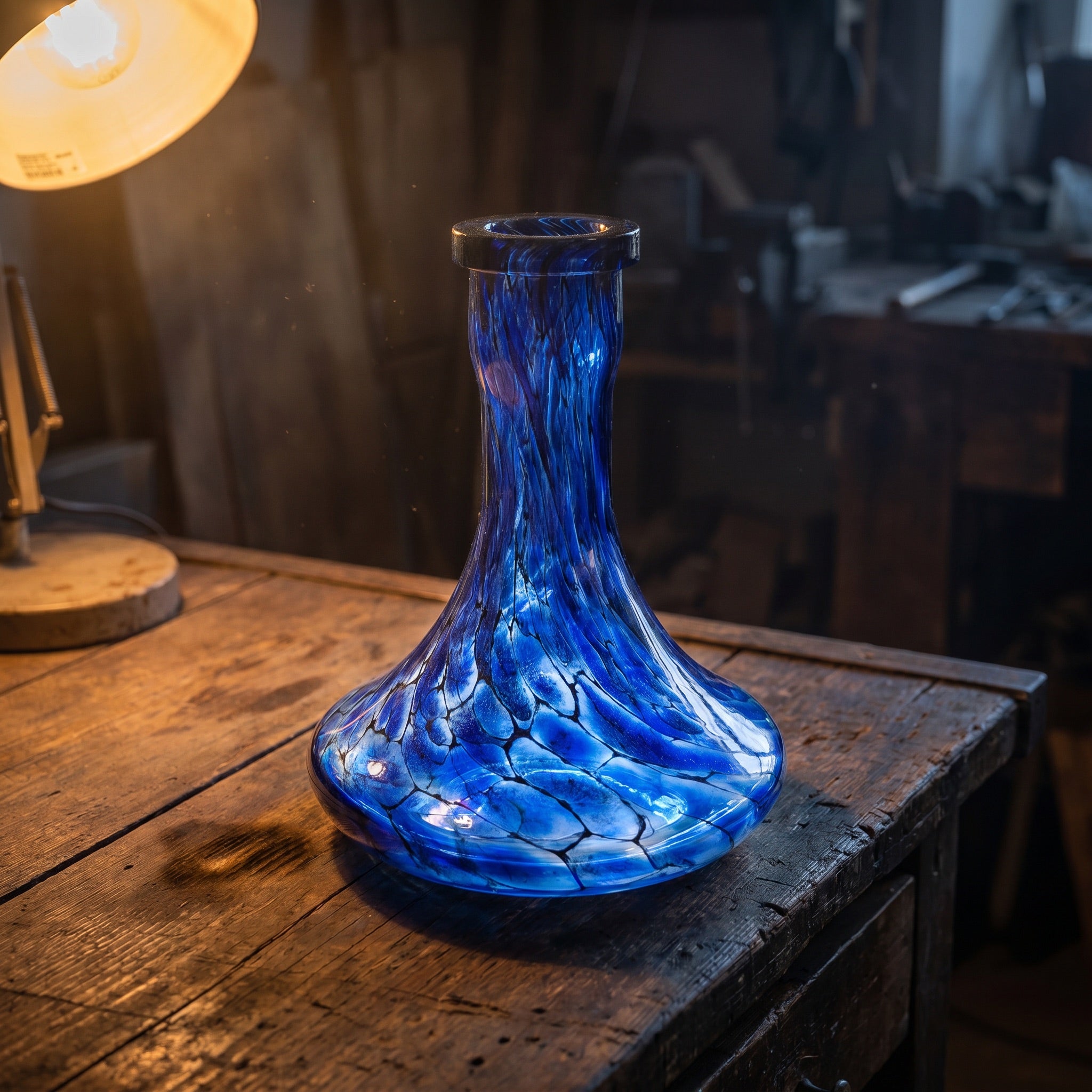Sapphire Web shisha vase by Essentials, hand-blown cobalt crackle glass on artisan workbench under warm lamp