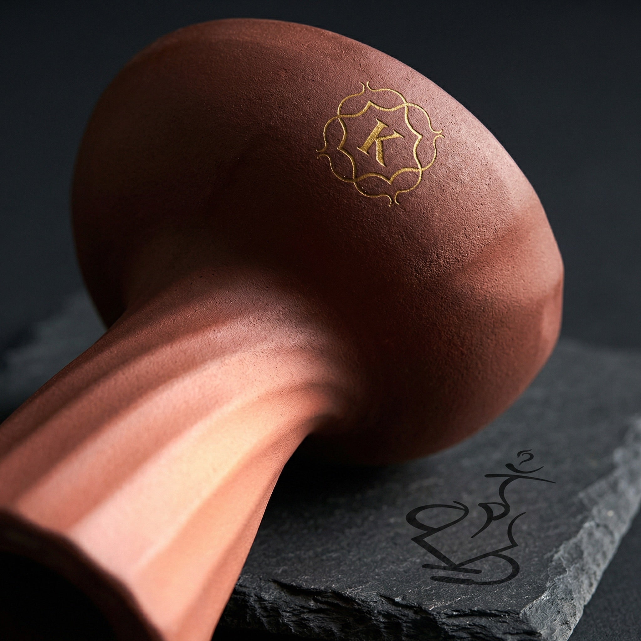 Close-up macro detail of Kaloud Samsaris Kore Qì porous red clay surface showing spiral twist ribbing grain texture and gold K crest