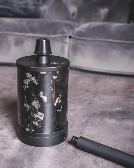 VYRO One V2 Forged Black shisha on a table next to a sofa